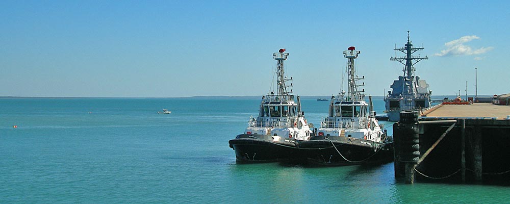 US Navy ship moored behind 2 tug boats in 
Darwin Harbour